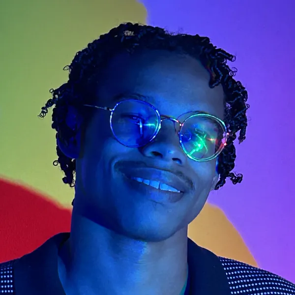 Jiggy, smiling in glasses under blue and purple light